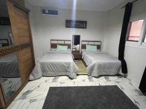 2 camas en una habitación con un cartel en la pared en Nubian Villa with Private Pool en Naj‘ al Aḩwāl