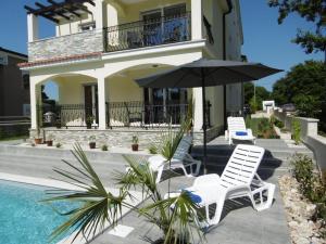 una casa con due sedie e un ombrellone accanto a una piscina di Villa Luka Apartment Gray mit Pool a Funtana