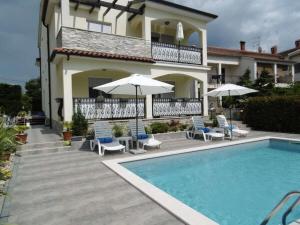una casa con piscina con sedie e ombrelloni di Villa Luka Apartment Gray mit Pool a Funtana