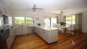 a large kitchen with white cabinets and a table at Le Belle Aimante, Magnetic Island in Horseshoe Bay