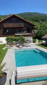 una gran piscina frente a una casa en Chalet avec vue panoramique sur les Montagnes du Mole et la chaîne des Aravis piscine chauffée à 5 min des pistes de la station des Brasses en Viuz-en-Sallaz