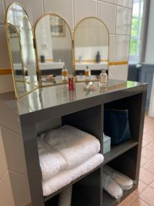 a bathroom with a vanity with mirrors and towels at Hôtel Particulier, Maison Jazey. in Semur-en-Auxois