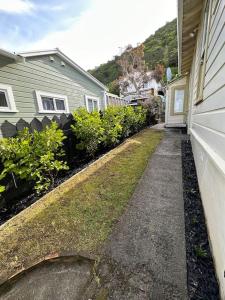 um passeio ao lado de uma casa com arbustos e um edifício em Cosy Coastal Villa in Lyall Bay em Wellington