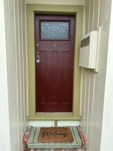 een rode deur met een bord voor een huis bij Cosy Coastal Villa in Lyall Bay in Wellington