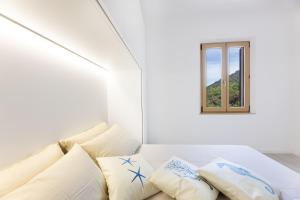 Habitación blanca con sofá y ventana en casa panoramica bouganville, en SantʼAndrea