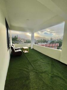 ein Wohnzimmer mit grünem Teppichboden und einem Fenster in der Unterkunft Blue Sky Hotel & Restaurant in Skardu