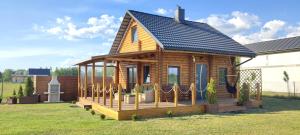 a log cabin with a porch on a yard at Sosnowa Chatka in Pilchy