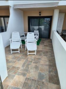 un patio con sillas blancas y una mesa en Apartment South Tenerife, en San Miguel de Abona
