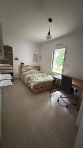 Schlafzimmer mit einem Bett, einem Schreibtisch und einem Stuhl in der Unterkunft Maison récente 3 chambres dont 1 suite parentale in Saint-Sauveur-dʼAunis