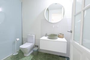 uma casa de banho branca com um WC e um espelho. em RaíZes 22 - Apartamento 5 em Puebla de Don Fadrique