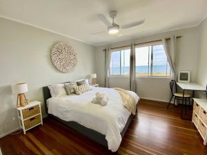 ein Schlafzimmer mit Bett, Schreibtisch und Fenster in der Unterkunft Pet & Family Friendly Ocean Front Beach Cottage in Bargara