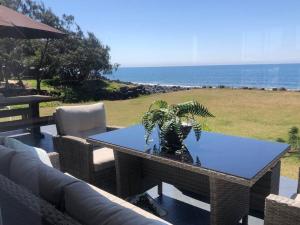 einen Tisch mit einer Topfpflanze auf einer Terrasse in der Unterkunft Pet & Family Friendly Ocean Front Beach Cottage in Bargara