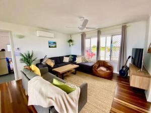 ein Wohnzimmer mit Sofa und Tisch in der Unterkunft Pet & Family Friendly Ocean Front Beach Cottage in Bargara