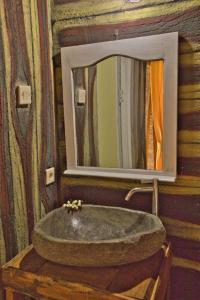 La salle de bains est pourvue d'un lavabo en pierre et d'un miroir. dans l'établissement Dira Bungalows, à Tetebatu