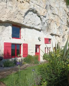 Casa de piedra con ventanas rojas y pared de piedra en Gite des Perreyeurs - maison troglodyte avec vue sur Loire en Montsoreau