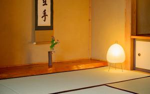 une chambre avec une lampe et un vase avec une plante dans l'établissement ZEN&BED Bogetsu-An, à Koshu