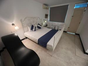 um quarto com uma cama branca e uma cadeira preta em Beverly Villa em Colombo