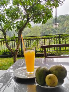 un vaso de zumo de naranja y algo de fruta en una mesa en Jacks Lounge and Hotel, en Kandy