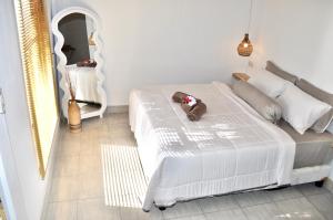 a teddy bear sitting on a bed in a bedroom at Ripbowl Guest House in Selong Belanak