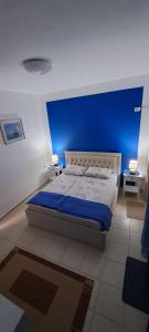a bedroom with a large bed with a blue wall at Seaside Apartment Plazhi vjeter in Vlorë