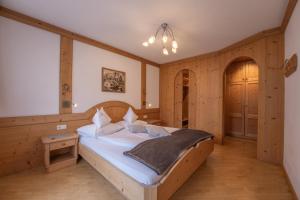 - une chambre avec un lit dans une pièce dotée de murs en bois dans l'établissement Residence Burghof, à Alpe di Siusi