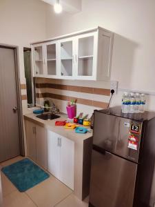 a kitchen with white cabinets and a stainless steel refrigerator at Idea Homestay 2 in Ipoh