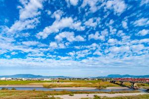 a bridge over a river under a blue sky with clouds at Yumoto Kobayashi in Kurume