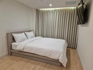 a bedroom with a bed with white sheets and a window at Gwang Jang Hotel in Busan