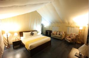 a bedroom with a bed and a couch in a tent at Coffeeberry Hills Chikamagalur in Chikmagalūr