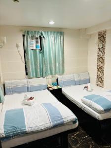 2 camas en una habitación con ventana en Holland Guest House, en Hong Kong