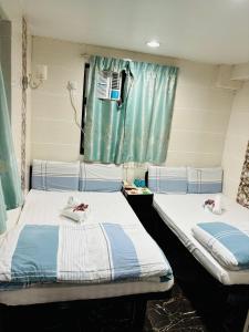 2 camas en una habitación de hospital con cortinas azules en Holland Guest House, en Hong Kong