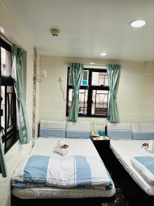 2 camas en una habitación con cortinas azules en Holland Guest House, en Hong Kong