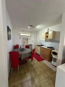 eine Küche und ein Esszimmer mit einem Tisch und roten Stühlen in der Unterkunft Day & Night Apartment in Ćuprija