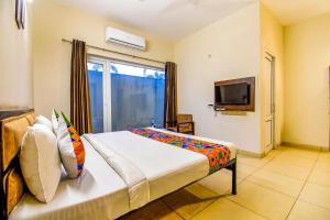 1 dormitorio con 1 cama, ventana y TV en FabHotel G-5 Villa, en Ludhiana