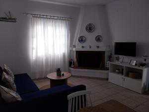 Kasi's nature home في كيثيرا: غرفة معيشة مع أريكة زرقاء وتلفزيون