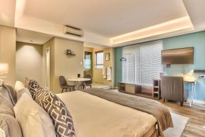 um quarto de hotel com uma cama grande e uma mesa em WINK Aparthotel Foreshore em Cidade do Cabo