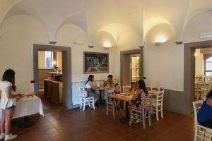 a group of people sitting at tables in a restaurant at Ostello Palazzo Pierantoni in Foligno