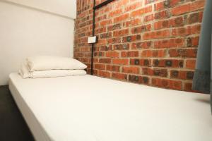 a bedroom with a brick wall and a white mattress at Suite 18 Boutique Hotel in Kuala Terengganu