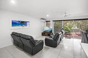 a living room with two leather chairs and a flat screen tv at Diamond Beach 35 in Gold Coast