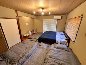 two beds in a small room with two windows at 100泊で完成する民泊 in Takamori