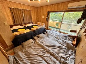 two beds in a room with a large window at 100泊で完成する民泊 in Takamori