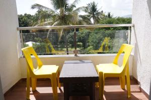 a balcony with two yellow chairs and a table and a window at Hotel MADHAVAN INN in Wai