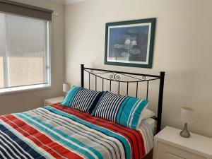 a bedroom with a bed with a striped blanket and a window at Lakes Entrance Views in Lakes Entrance