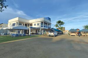 a large white building with cars parked in front of it at Hip Nautic Beach Resort powered by Cocotel in Lian