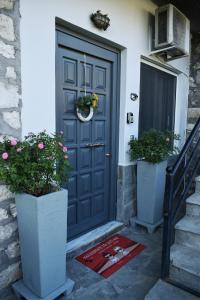 a black door with two potted plants on the steps at Elichrysos GuestHouse Konitsa in Konitsa