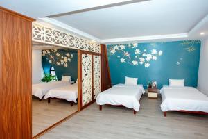 three beds in a room with flowers on the wall at Song Anh Hotel Tuần Châu in Ha Long