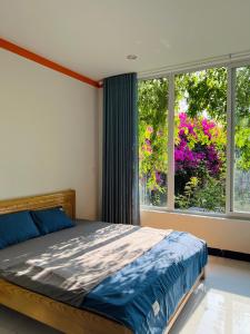 a bedroom with a bed and a window with flowers at Thanh's House Homestay Buôn Ma Thuột in Buôn Dhă Prŏng