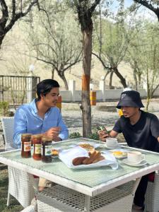 a couple of people sitting at a table eating food at MONTAGNA PODS in Skardu