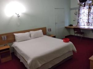 a bedroom with a white bed with a red bowl on it at Brackendene Lodge in Gaborone