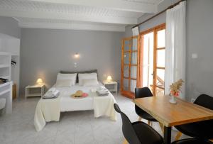 a bedroom with a white bed with a table and chairs at Albouro Seafront Apartments in Katelios